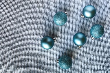 Örgü süveterin yüzeyinde mavi parlak toplar.