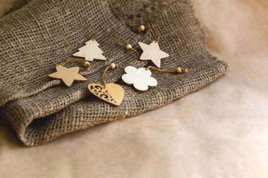 Noel ağacı, kalp, çiçek ve yıldızlar şeklinde farklı ahşap oyuncakların arkaplanı kraft kağıdındaki çuval bezi kumaşında kahverengi kare şeklinde uzanır.