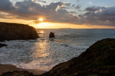Sunset landscape on the ocean with sheer cliffs and foamy waves