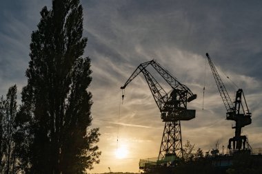 Gdansk, Polonya. 2021 Eski gemi yapım şirketi. Tekne yapımı için vinçler. Gün batımında.