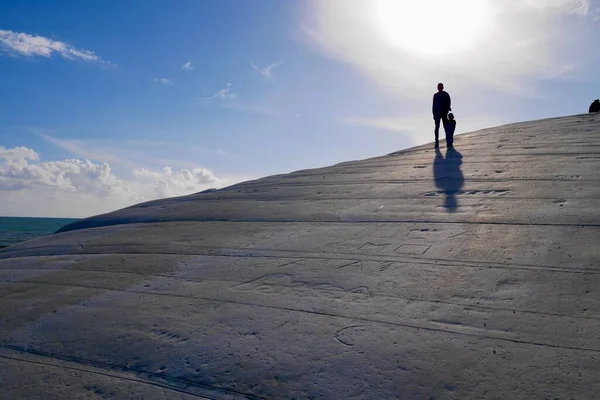 Silhuetas de pessoas em pé nas escadas de pedra calcária branca de Scala dei Turchi. Atração turística popular perto de Agrigento, Sicília, Itália. — Fotografia de Stock