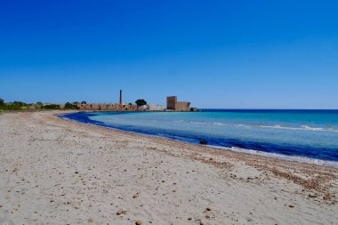 Turkuaz suyu ve Riserva Naturale Oasi Faunistica di Vendicari 'deki terk edilmiş ton balığı fabrikasıyla kumsal Syracuse, Sicilya, İtalya.