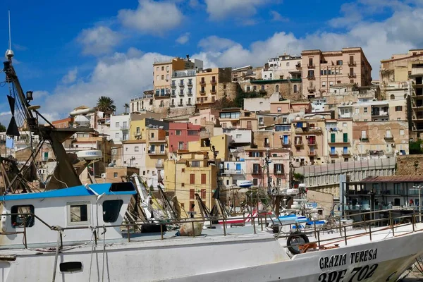 Sciacca, Sicília, Itália, 24.03.2018. Barcos de pesca no porto com casas coloridas da cidade velha no fundo. — Fotografia de Stock