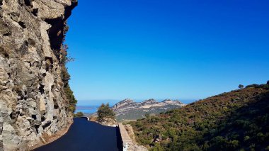 Açık ve güneşli bir sabahta Patrimonio tepelerinin nefes kesici manzarasıyla Balagne 'da dar ve dolambaçlı bir dağ yolu. Korsika, Fransa.
