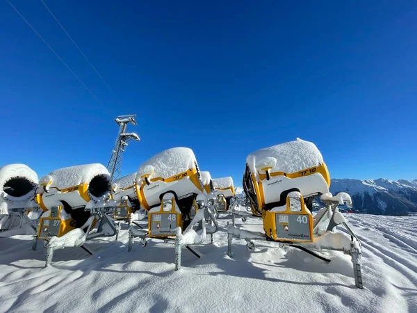 Golm, Austria, 12.12.2021. Wiele żółtych dział śnieżnych zaparkowanych w ośrodku narciarskim przed błękitnym niebem. — Zdjęcie stockowe