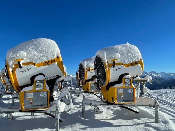 Golm, Austria, 12.12.2021. Grupa żółtych dział śnieżnych zaparkowanych w ośrodku narciarskim przed błękitnym niebem. — Zdjęcie stockowe