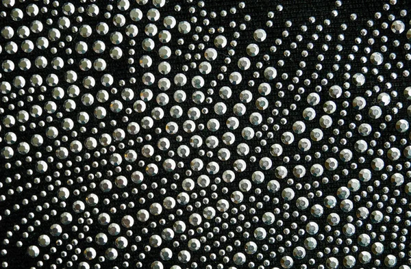 Close up of glittering beads, sequins, on black wool, wallpaper background. — Stock Photo, Image