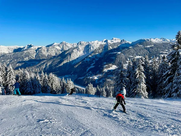 Esquiadores nos Alpes Austríacos em um dia ensolarado de inverno, vista panorâmica deslumbrante de montanhas cobertas de neve. — Fotografia de Stock