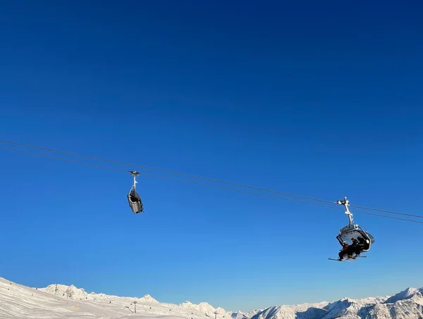 Wyciąg krzesełkowy i pokryty śniegiem grzbiet górski na tle błękitnego nieba w ośrodku narciarskim Golm, Montafon, Austria. — Zdjęcie stockowe