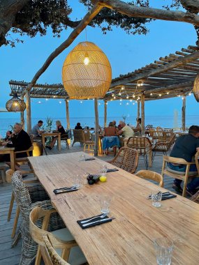 Cervione, Korsika, Fransa, 14.07.2021. Campo Mare restoranında romantik deniz kenarında akşam yemeği. Dikey.