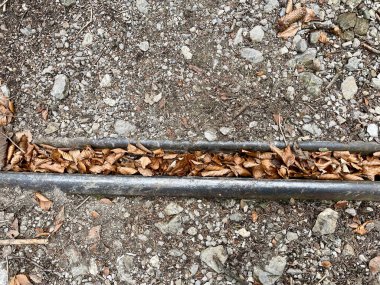 Sonbahar yaprakları ve toprak çakıl yollarıyla dolu yağmur oluğuna yakın..