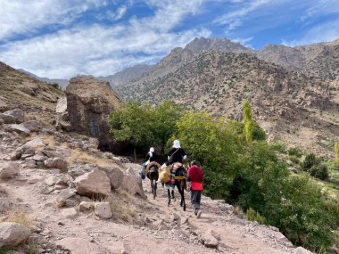 Toubkal Ulusal Parkı, Fas, 25.10.2021. Yüksek Atlas Dağları 'ndaki katırların üzerindeki yerliler, İslam öncesi bir marabut türbesi olan Sidi Chamharouch' a gidiyorlar..