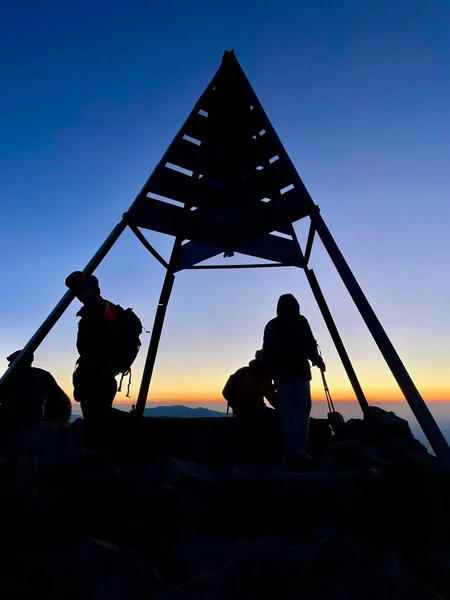 Πεζοπόροι στέκονται στην κορυφή του Djebel Toubkal, του ψηλότερου βουνού του Μαρόκου, την ανατολή του ηλίου. Κατακόρυφο κοντινό. — Φωτογραφία Αρχείου