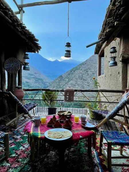 Delicious Moroccan breakfast with spectacular Toubkal view. Beautifully decorated rooftop terrace at Berber homestay in the High Atlas Mountains. Imlil Valley, Morocco.