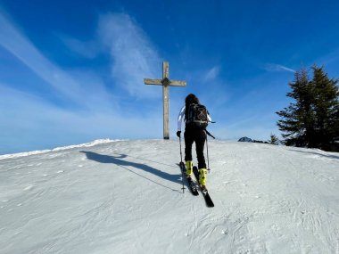 Avusturya Alpleri 'nde tahta zirve haçına yaklaşan kayak turisti. Görüşürüz, Vorarlberg, Avusturya.