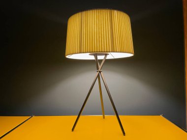 Gece mavi duvarın önündeki sarı büfede aydınlatılmış kumaş masa lambası..