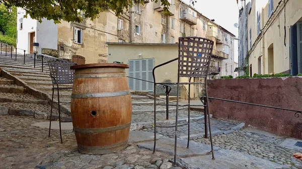 Uteservering av höftbaren, barstolar runt trätunnan i natursköna kvarteren Corte, Korsika, Frankrike. — Stockfoto