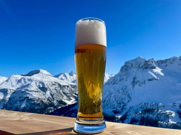 Apres sciare nelle Alpi austriache. Bicchiere di birra di grano sulla recinzione di legno in una giornata di sole. Località sciistica di Lech Zuers, parte del comprensorio sciistico di Arlberg. — Foto Stock