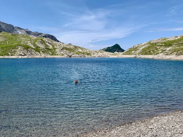 Mulher nadando em Butzensee verde-esmeralda na região de Arlberg, perto de Lech. Vorarlberg, Áustria. — Fotografia de Stock