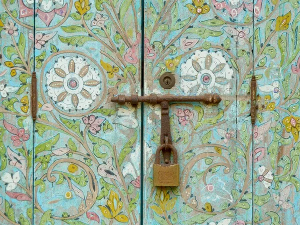 Закрыть разноцветную деревянную дверь красивым расписным орнаментом и железным замком. Рабат, Морено. — стоковое фото