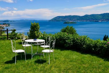 Verbania 'nın yukarısındaki Maggiore Gölü ve Barromean adalarına bakan bir tepede beyaz antika demir bir masa. Piedmont, İtalya. Yüksek kalite fotoğraf