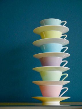 Sarı masanın üzerinde benzin zeminine karşı pastel renkli kahve fincanları yığını. Yüksek kalite fotoğraf