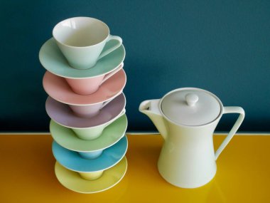 Renkli çay fincanları ve çay demliği yığını sarı masada, benzin zeminine karşı. Öğleden sonra çay partisi. Yüksek kalite fotoğraf