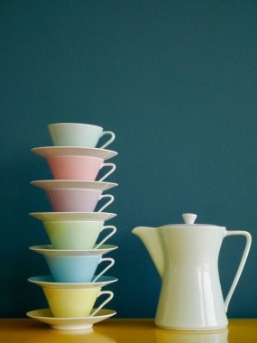 Renkli çay fincanları ve çay demlikleri sarı masanın üzerinde, benzin zeminine karşı. Öğleden sonra çay partisi. Dikey. Yüksek kalite fotoğraf