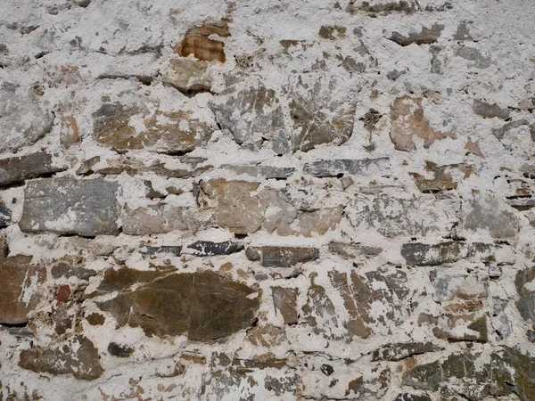 古い納屋のファサードを閉じます。崩壊した白い石膏と石の壁. — ストック写真