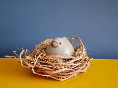 Sarı büfedeki söğüt yuvasında mavi duvara karşı seramik Paskalya tavuğu. Yüksek kalite fotoğraf