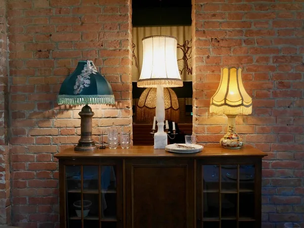 Interior design, vintage lamps on wooden sideboard against red brick wall. High quality photo