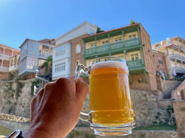 Woman holding a glass of beer, old sulphur baths district Abanotubani, Tbilisi, Georgia, in the background. High quality photo