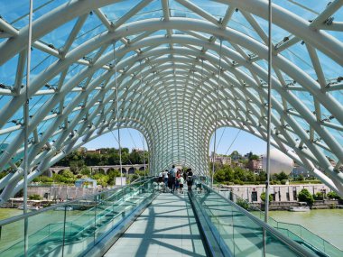 İnsanlar Gürcistan 'ın Tiflis kentindeki Kura nehri üzerindeki Barış Köprüsü' nde yürüyor. Yüksek kalite fotoğraf