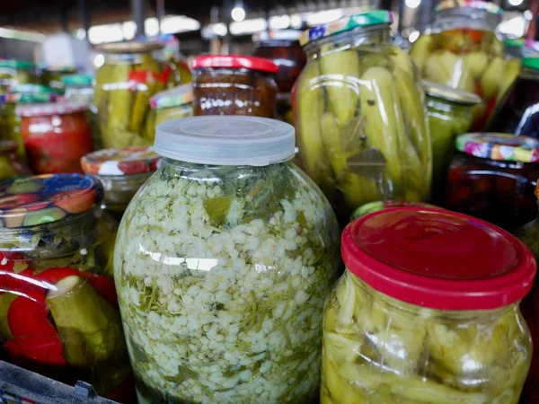Jars with homemade pickled vegetables on sale at local farmers market. High quality photo