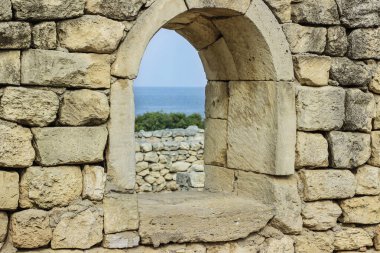 Pencereden bak. Penceresi ve deniz manzaralı antik taş duvar.