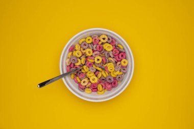 Mısır gevreği kasede. Renkli Meyveli Gevrek Döngüsü Arkaplanı. Tepeden tırnağa düz, tatlı müsli. Tatlı kahvaltı kasesinde.