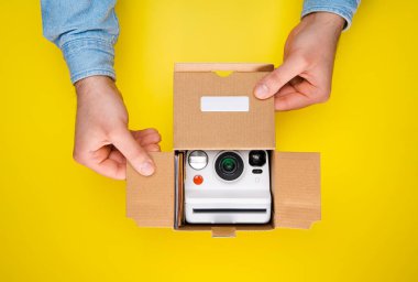 Sarı arka plandaki ürün paketini sonuna kadar açıyorum. Eller yeni bir ürün kutusu açıyor.