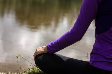 Sırtüstü oturmuş, gölün önünde meditasyon yapan bir kadın. Suda bulut yansımaları olan bir kadın. Özgürlük kavramı