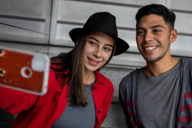 İki genç Latin Amerikalı kardeş birlikte vakit geçirip aile portresi çekiyorlar. Teknoloji konsepti.