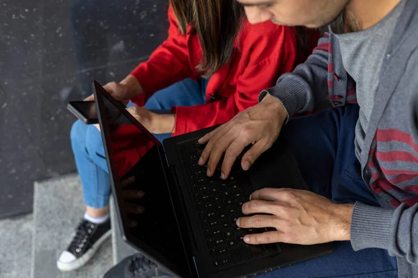 Laptop ve cep telefonuyla oturan iki genç Latin Amerikalı serbest yazar kardeş. Yukarıdan bak. Teknoloji konsepti.