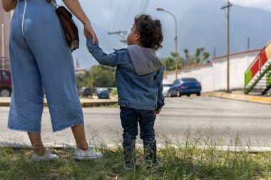 Latin Amerikalı anne ve oğlu karşıdan karşıya geçmek için el ele tutuşuyorlar. Yürüyüşe çıkmak, annelik.