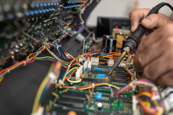 Hands of Latin American electronic technician repairing the circuit of a piano with soldering iron and tin in the service center. Concept repair, Music, electronic