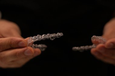 Elinde görünmez bir hizalayıcı tutan bir ortodonti uzmanının yakın çekimi. Görünmez ortodonti tekniği kavramı.