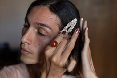 Genç travesti (22) odasında aksesuarlarını takıyor. Transseksüel Konsepti