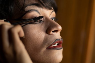 Genç travesti (26) odasında makyaj yapıyor. Transseksüel Konsepti