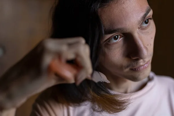 Genç transseksüel (22) adam saçını tarıyor. Transseksüel Konsepti