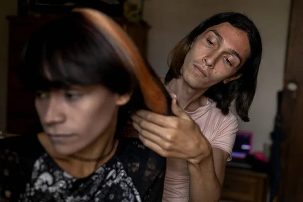 Genç bir transseksüel (26) erkeğe saçını taraması için başka bir transseksüel erkek yardım eder. Transseksüel Konsepti