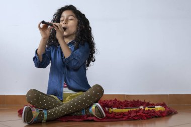 Latin Amerikalı kız pikolo kaydedicisi çalıyor.