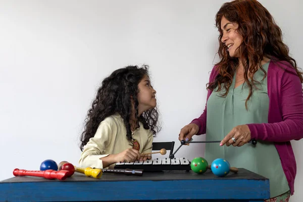 Latin American music teacher giving rhythmic music lessons with a xylophone