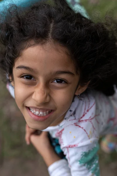 Latin American girl with positive attitude looks at camera while smiling. Top View